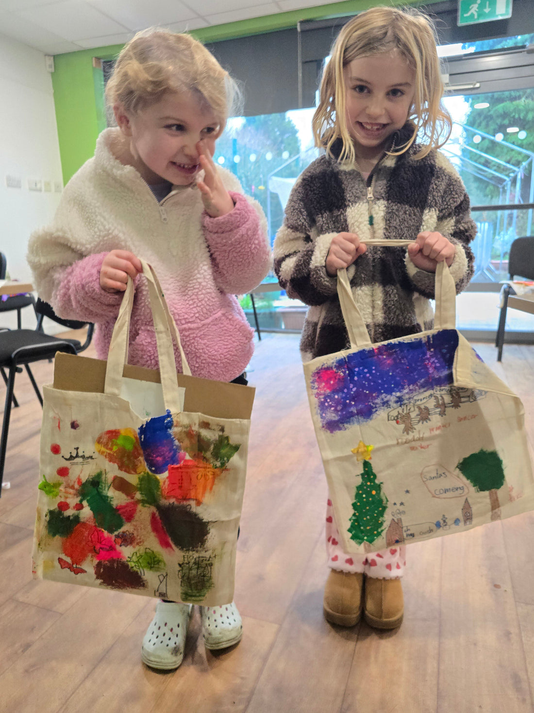 2 young girls standing next to each other showing their totebags form the afro-psychedelic tote-bag workshop session with Jasmin Issaka