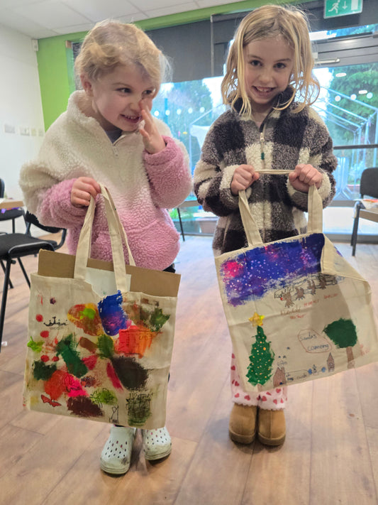 2 young girls standing next to each other showing their totebags form the afro-psychedelic tote-bag workshop session with Jasmin Issaka